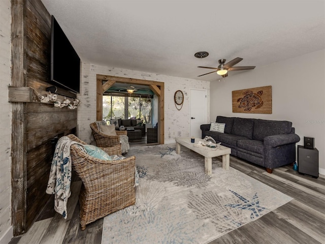 living room featuring visible vents, a textured ceiling, wood finished floors, a fireplace, and ceiling fan