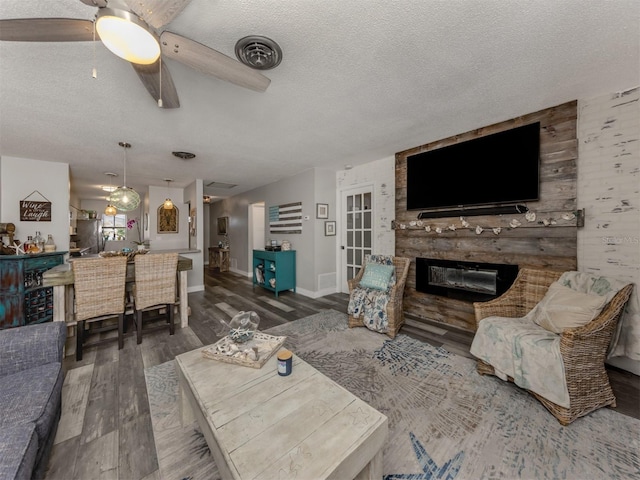 living room featuring a textured ceiling, wood finished floors, a fireplace, baseboards, and ceiling fan