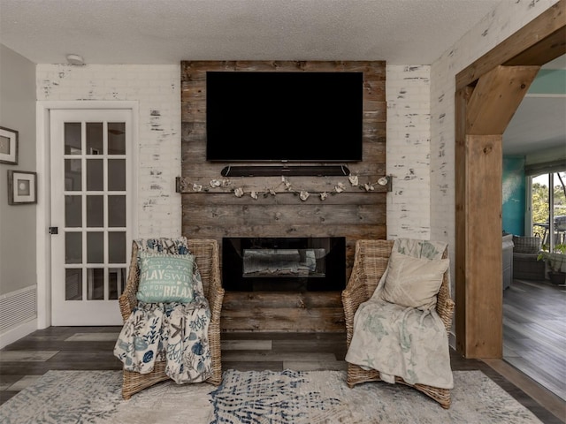 living area featuring a textured ceiling, a brick fireplace, and wood finished floors