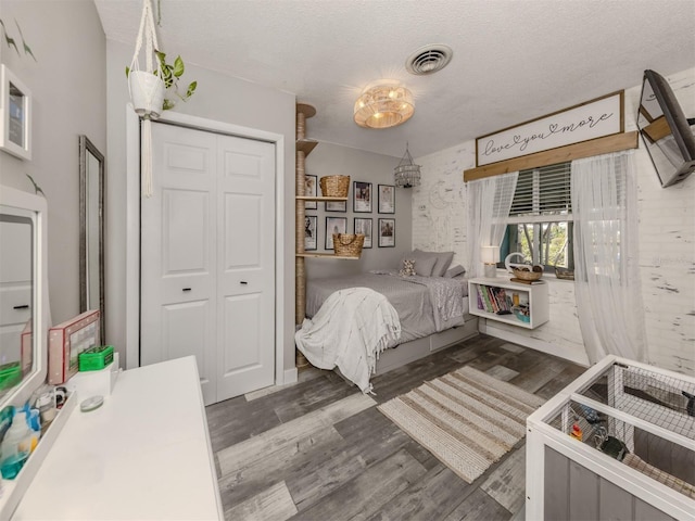 bedroom featuring dark wood finished floors, visible vents, a closet, and a textured ceiling