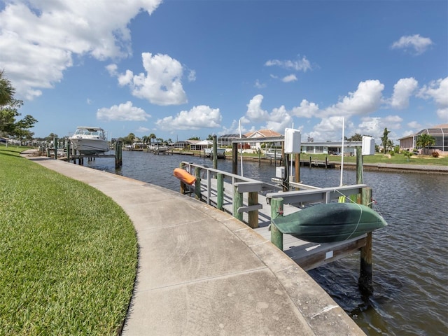 dock area featuring boat lift, a lawn, and a water view