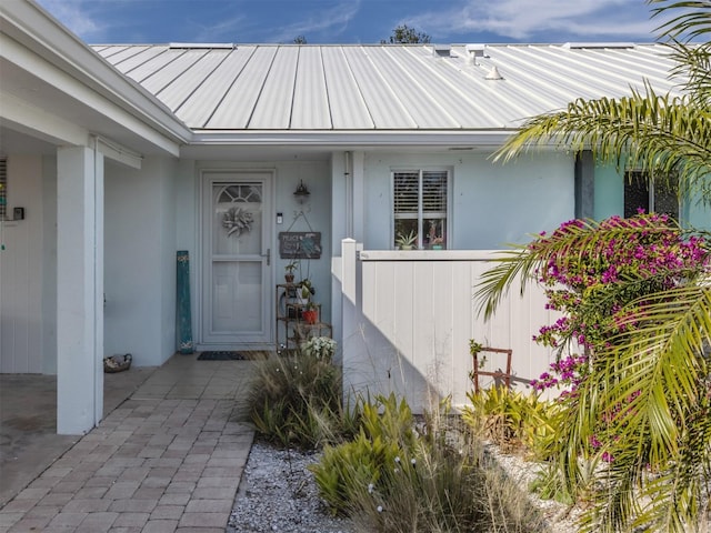 entrance to property featuring stucco siding, metal roof, and a standing seam roof