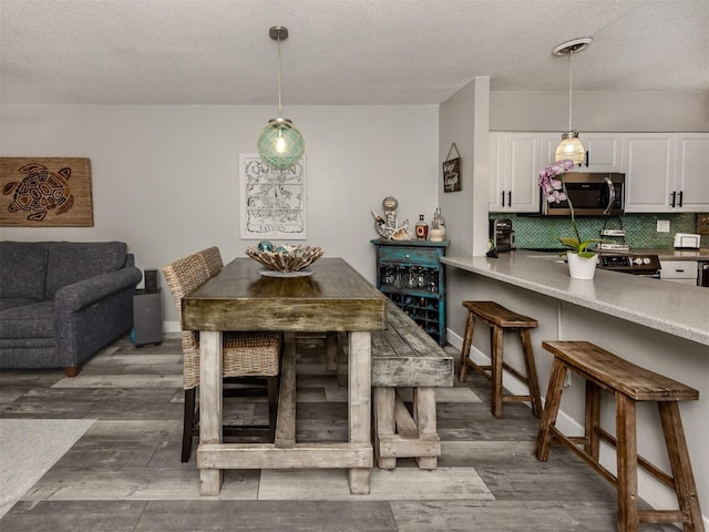 dining area with wood finished floors, baseboards, and a textured ceiling