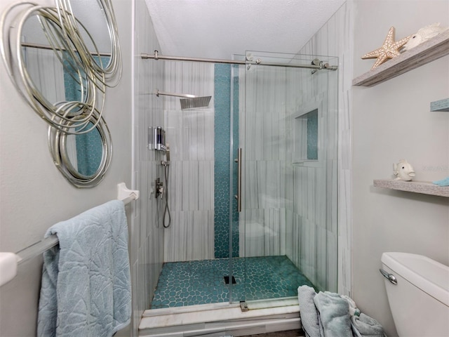 bathroom featuring toilet, a shower stall, and a textured ceiling