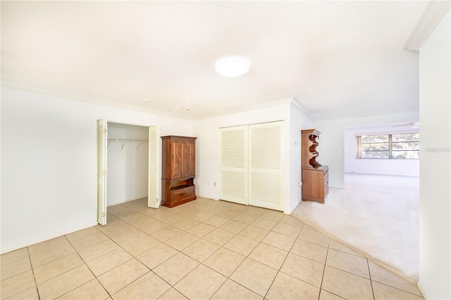 unfurnished bedroom with multiple closets, crown molding, and light tile patterned floors