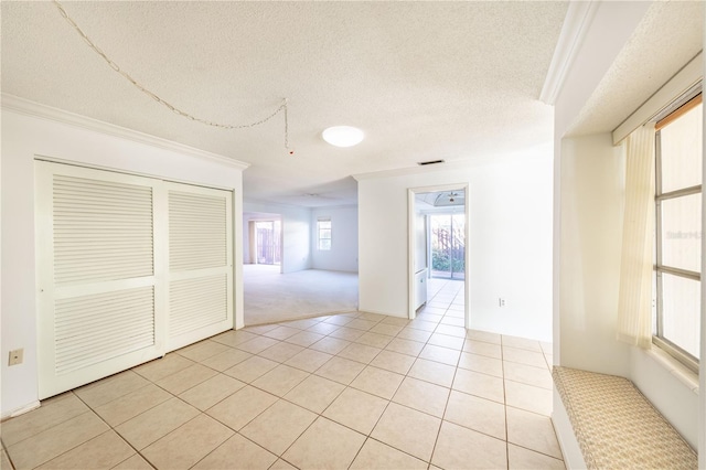 tiled spare room with crown molding and a textured ceiling