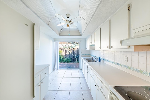 kitchen featuring sink, a raised ceiling, white cabinets, and ceiling fan