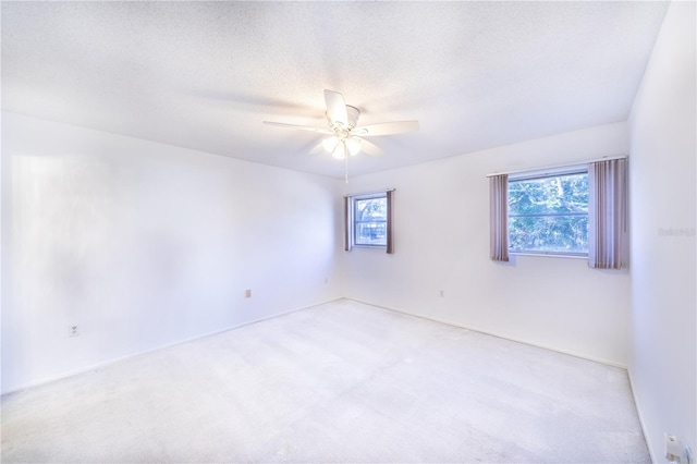 carpeted spare room featuring ceiling fan, a wealth of natural light, and a textured ceiling