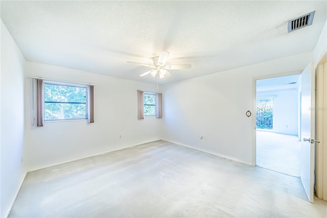 spare room featuring ceiling fan, light colored carpet, and a textured ceiling