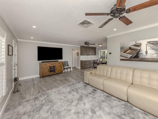 living room featuring ceiling fan, crown molding, and a textured ceiling