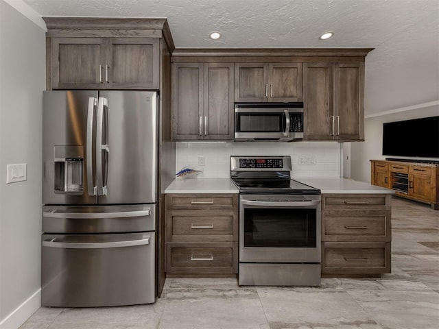 kitchen with dark brown cabinetry, appliances with stainless steel finishes, backsplash, and a textured ceiling