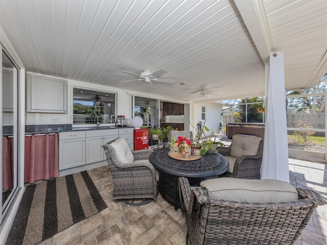 view of patio featuring sink, a hot tub, ceiling fan, and an outdoor kitchen