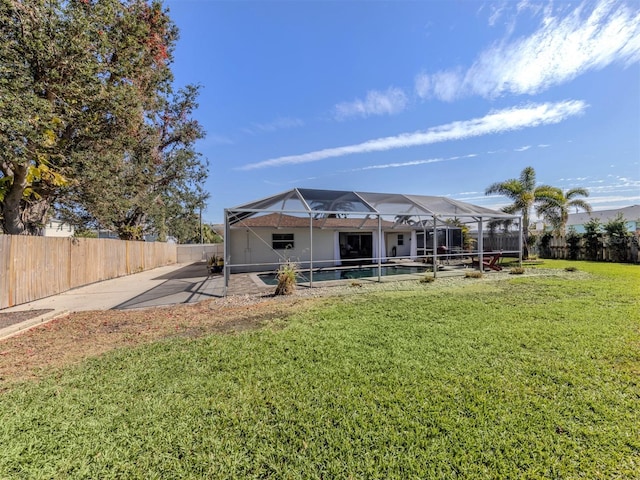 rear view of house with a yard, a patio area, and glass enclosure