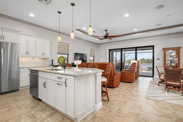 kitchen with white cabinetry, a kitchen island with sink, stainless steel appliances, light stone counters, and decorative light fixtures