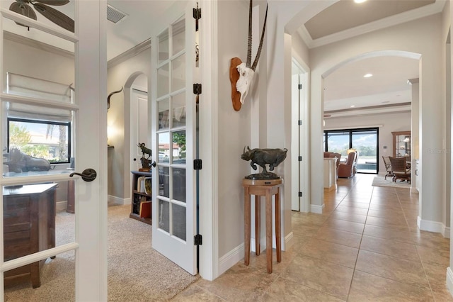 corridor featuring ornamental molding and light tile patterned floors