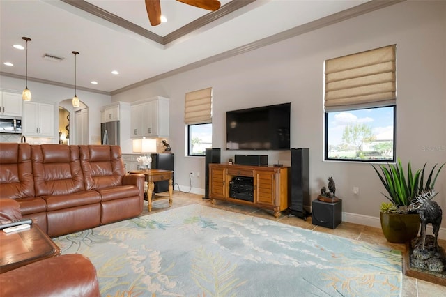 living room with light tile patterned flooring, ceiling fan, ornamental molding, and a tray ceiling