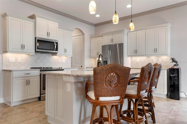 kitchen featuring light stone countertops, stainless steel appliances, white cabinets, and a center island with sink