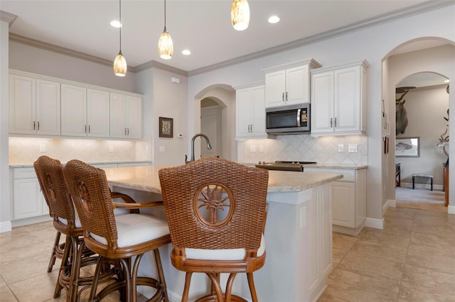 kitchen featuring white cabinetry, hanging light fixtures, light stone countertops, and a center island with sink