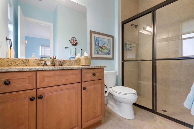 bathroom featuring a shower with door, vanity, tile patterned flooring, and toilet