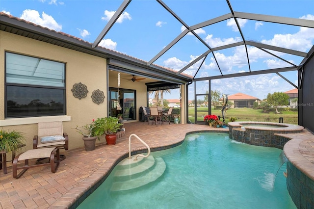 view of pool featuring ceiling fan, a patio, glass enclosure, pool water feature, and an in ground hot tub