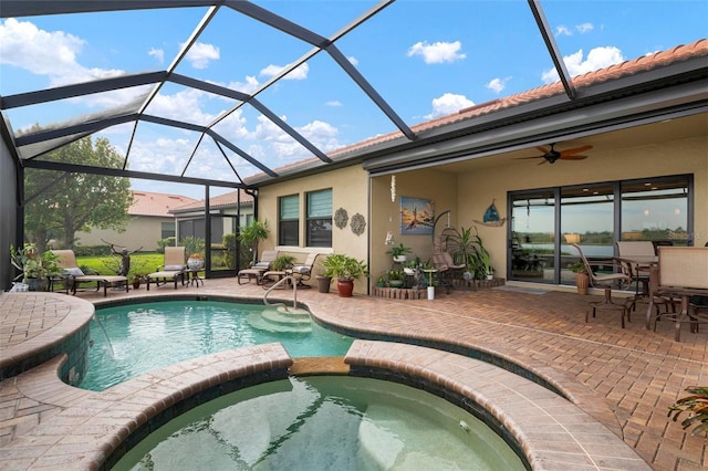 view of pool featuring ceiling fan, a patio, glass enclosure, and an in ground hot tub