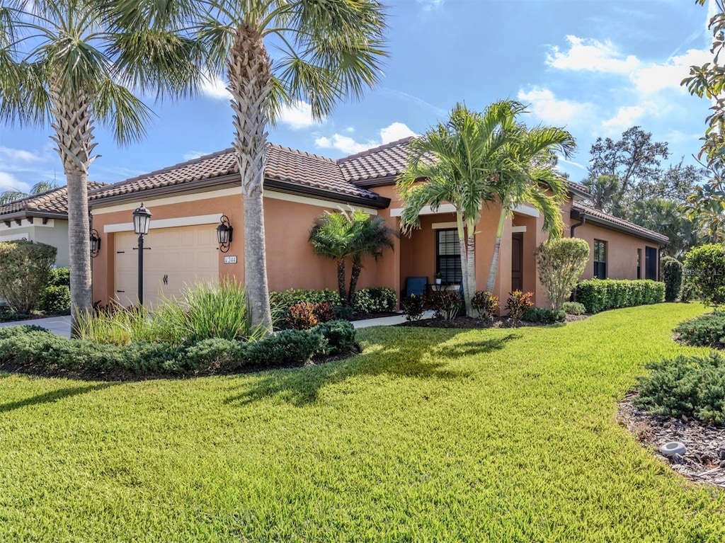 mediterranean / spanish home with a garage and a front lawn