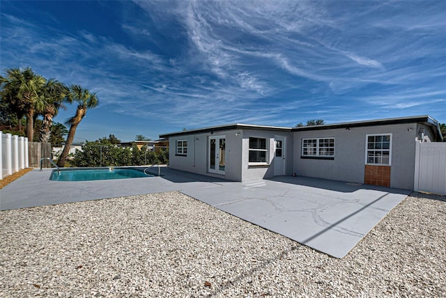 rear view of house featuring french doors, a fenced in pool, and a patio