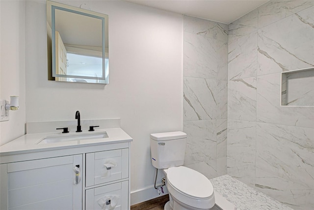 bathroom featuring tiled shower, vanity, and toilet