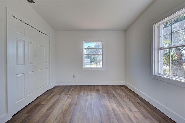 unfurnished bedroom with multiple windows and dark hardwood / wood-style flooring