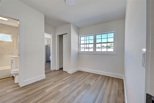 unfurnished bedroom featuring a closet, connected bathroom, and light hardwood / wood-style flooring