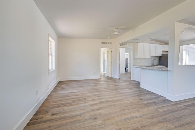 unfurnished living room featuring sink and light hardwood / wood-style flooring