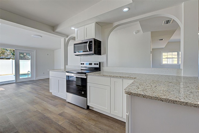 kitchen featuring white cabinetry, light hardwood / wood-style flooring, appliances with stainless steel finishes, kitchen peninsula, and light stone countertops