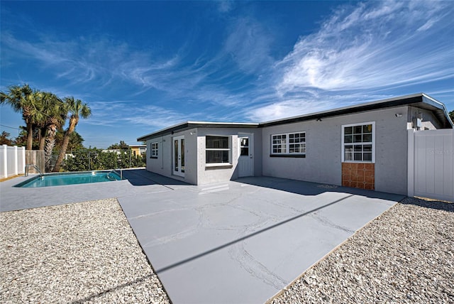 rear view of property featuring a fenced in pool and a patio