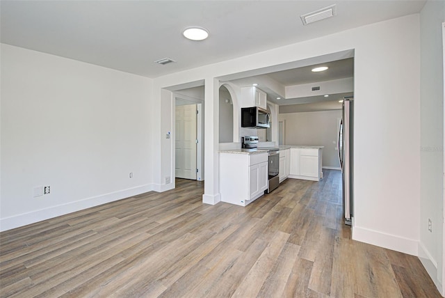 interior space with stainless steel appliances, white cabinets, and light wood-type flooring