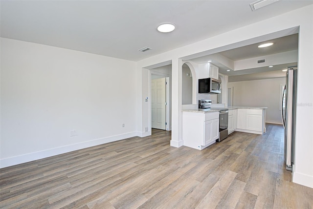 kitchen featuring light stone counters, appliances with stainless steel finishes, light wood-type flooring, and white cabinets