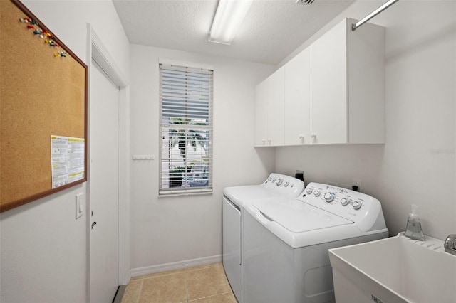 clothes washing area featuring sink, cabinets, a textured ceiling, light tile patterned flooring, and separate washer and dryer