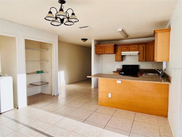 kitchen with washer / dryer, light tile patterned flooring, stove, and kitchen peninsula