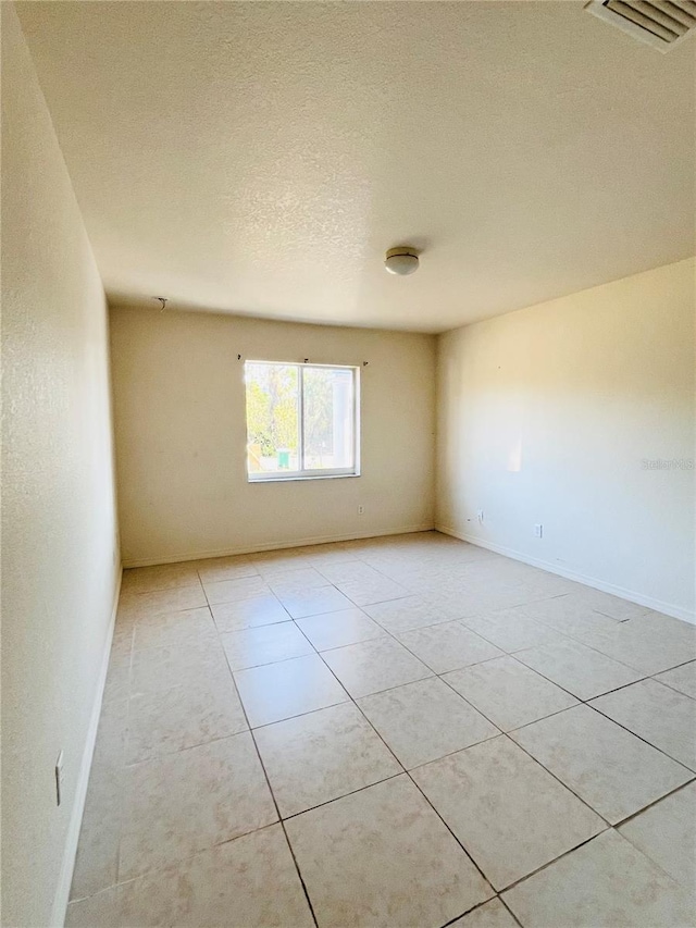 tiled empty room with a textured ceiling