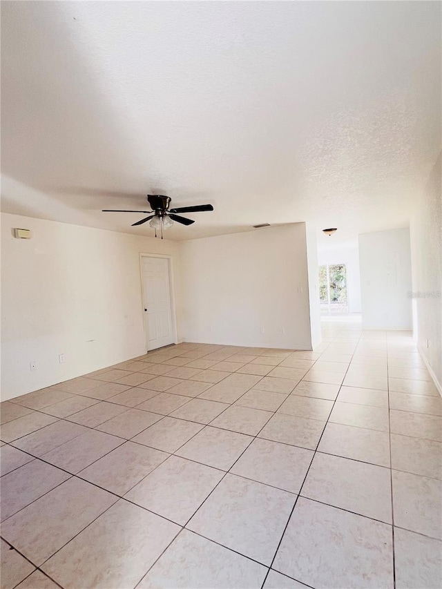 empty room featuring ceiling fan, a textured ceiling, and light tile patterned floors