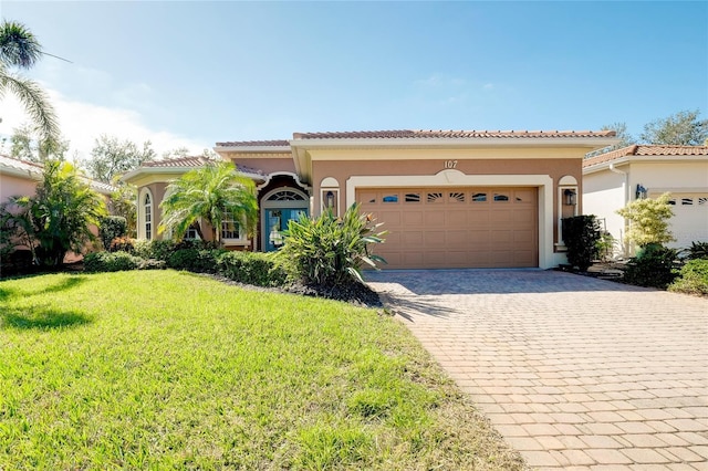 mediterranean / spanish home with a garage, a front lawn, decorative driveway, and stucco siding