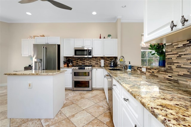 kitchen with stainless steel appliances, a sink, white cabinets, and light stone countertops