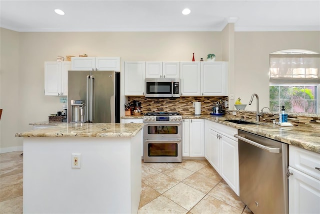 kitchen with white cabinets, light stone counters, stainless steel appliances, and a sink