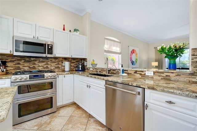 kitchen featuring appliances with stainless steel finishes, white cabinets, a sink, and backsplash