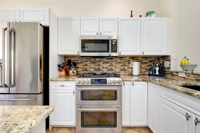 kitchen with stainless steel appliances, tasteful backsplash, white cabinetry, and light stone counters