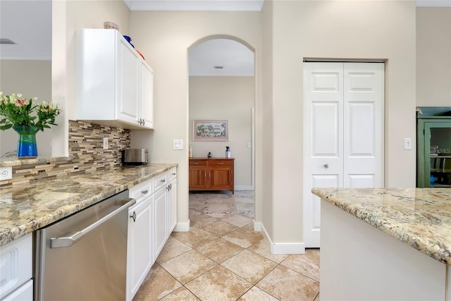 kitchen featuring arched walkways, white cabinetry, stainless steel dishwasher, light stone countertops, and tasteful backsplash