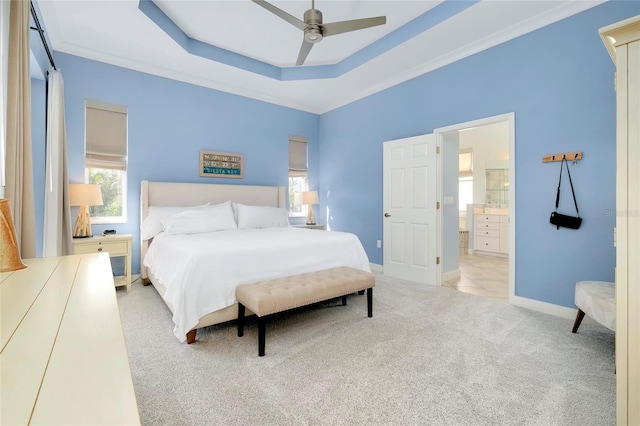 bedroom with light carpet, baseboards, a raised ceiling, connected bathroom, and ceiling fan