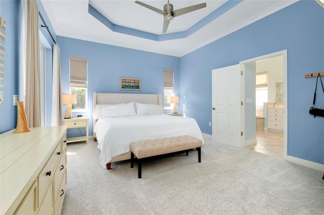 bedroom featuring light carpet, multiple windows, a raised ceiling, and baseboards