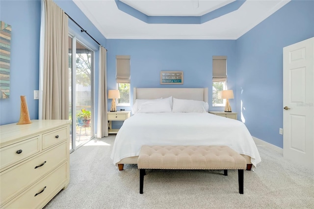 bedroom featuring a tray ceiling, light carpet, and multiple windows