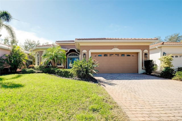 mediterranean / spanish house featuring a garage, a front yard, decorative driveway, and stucco siding