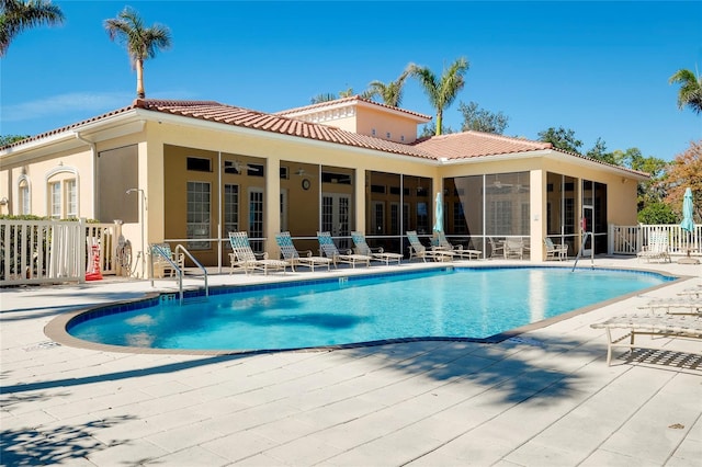 pool featuring a sunroom, a patio area, fence, and french doors